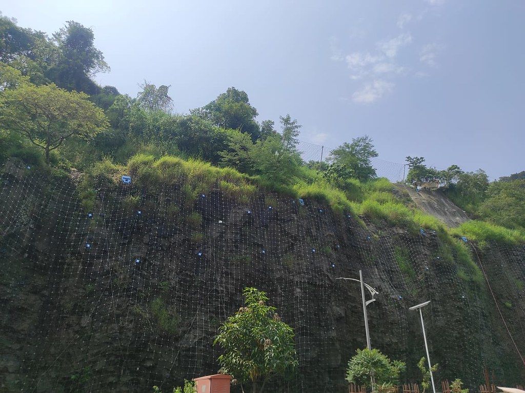 Rock slope fitted with protective netting and rockfall sensors